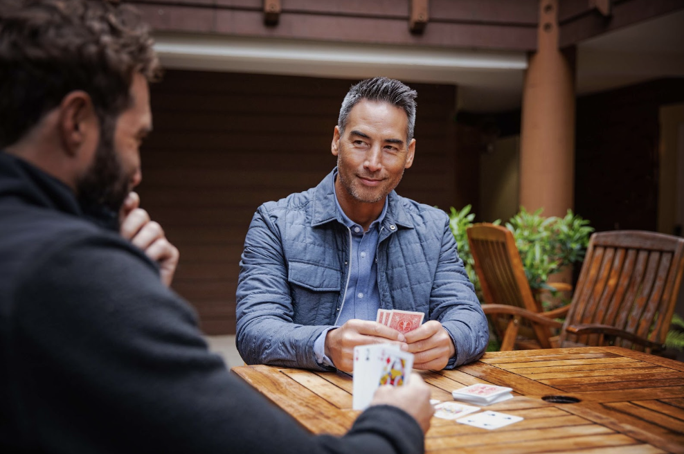 two men playing cards wearing cutter and buck outerwear