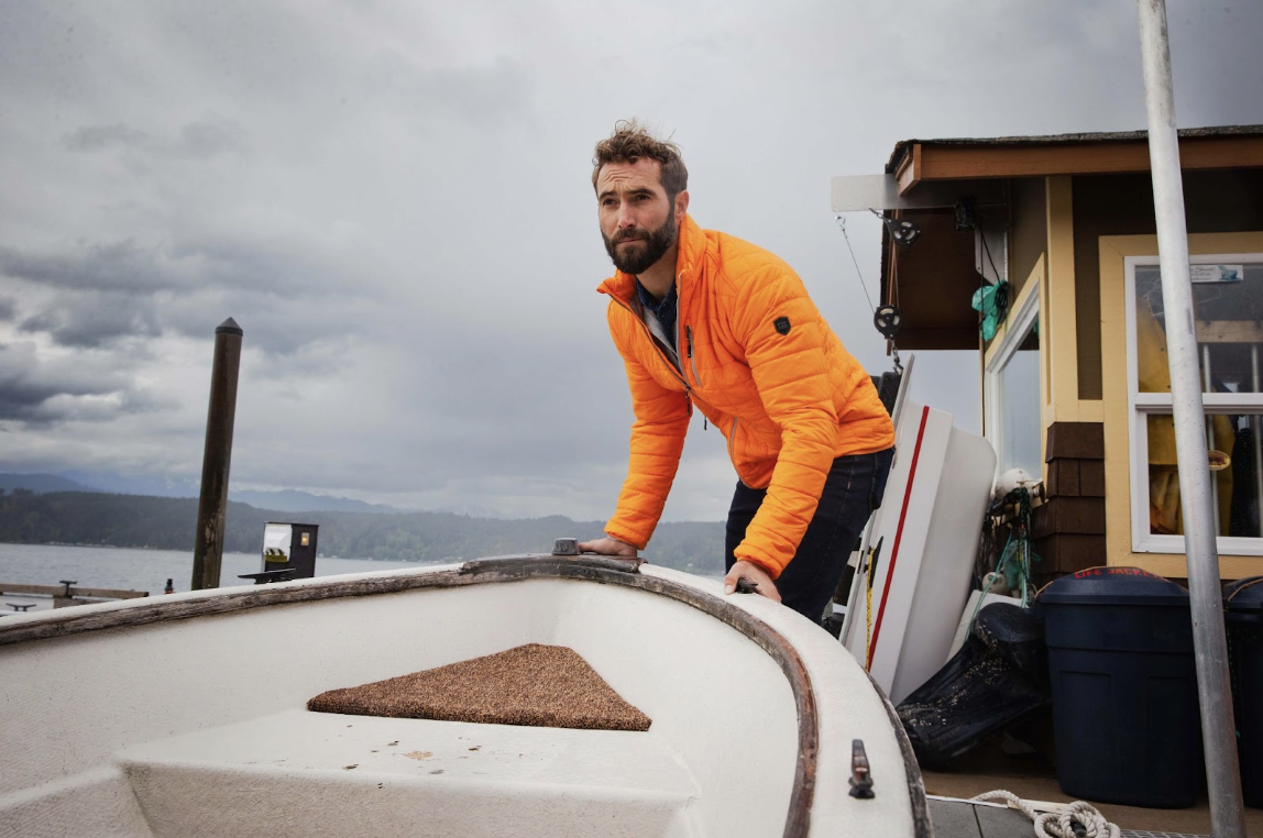 man pushing boat wearing insulated jacket