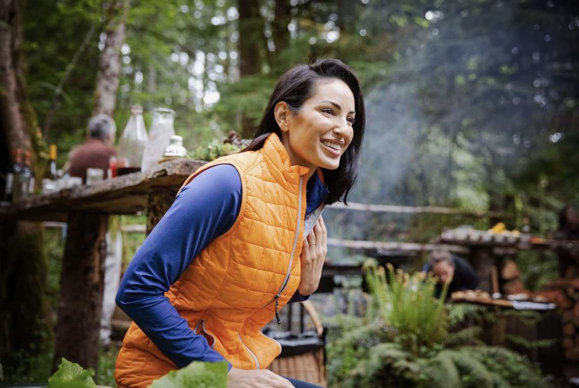 woman at campfire wearing orange puffer vest