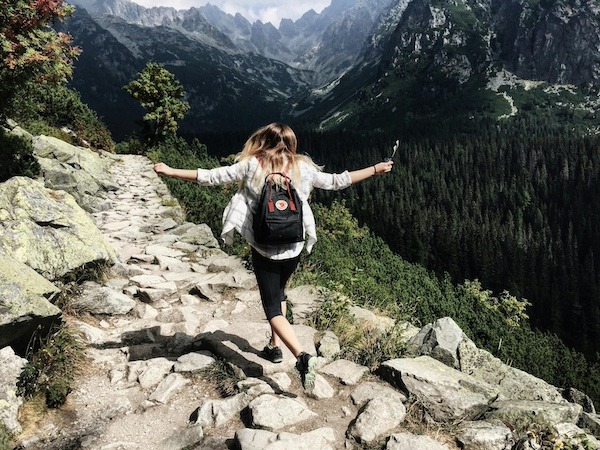 Woman running across mountain rocks on National Trails Dats